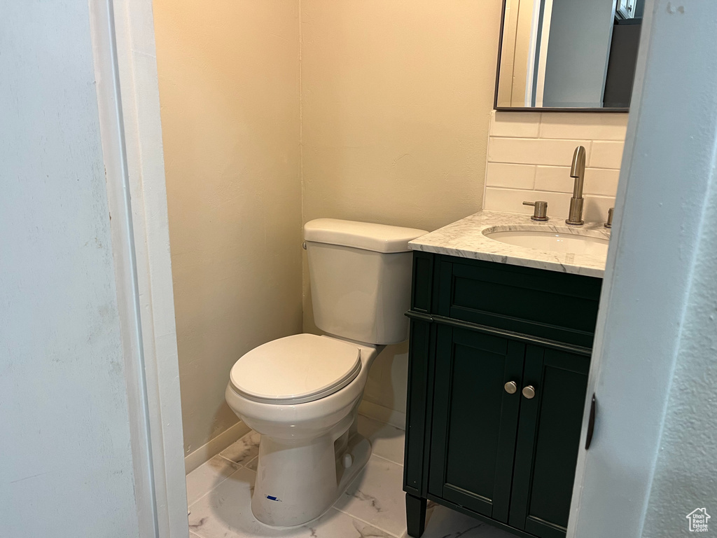 Bathroom featuring vanity, toilet, and tasteful backsplash