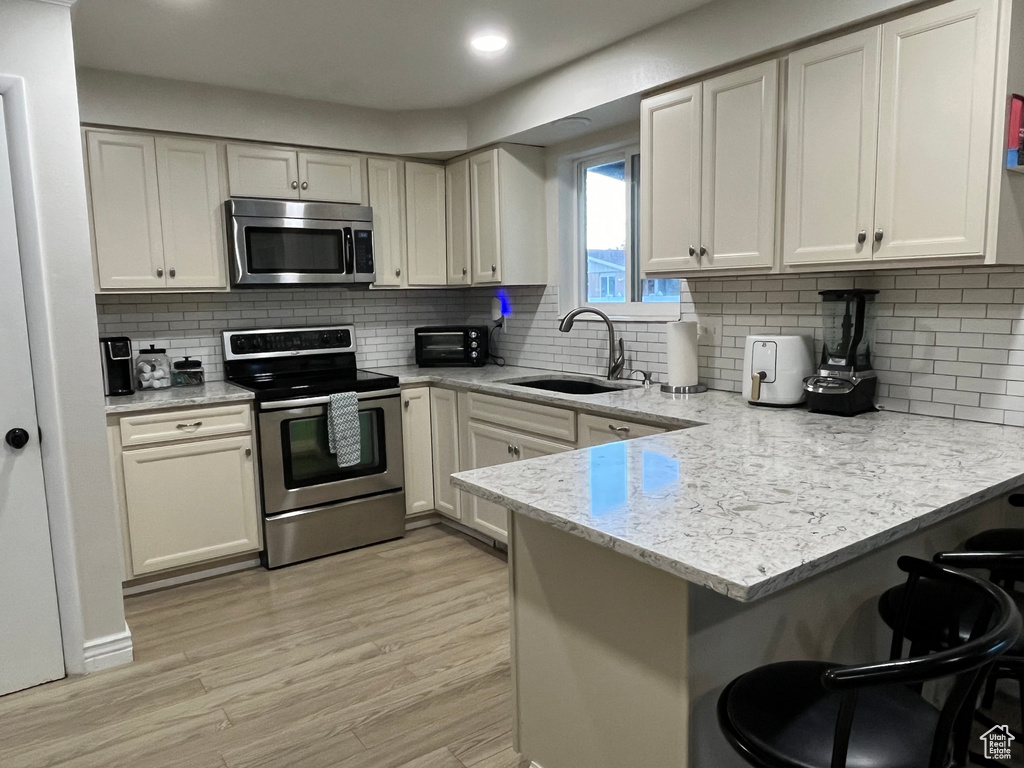 Kitchen with kitchen peninsula, tasteful backsplash, stainless steel appliances, and sink