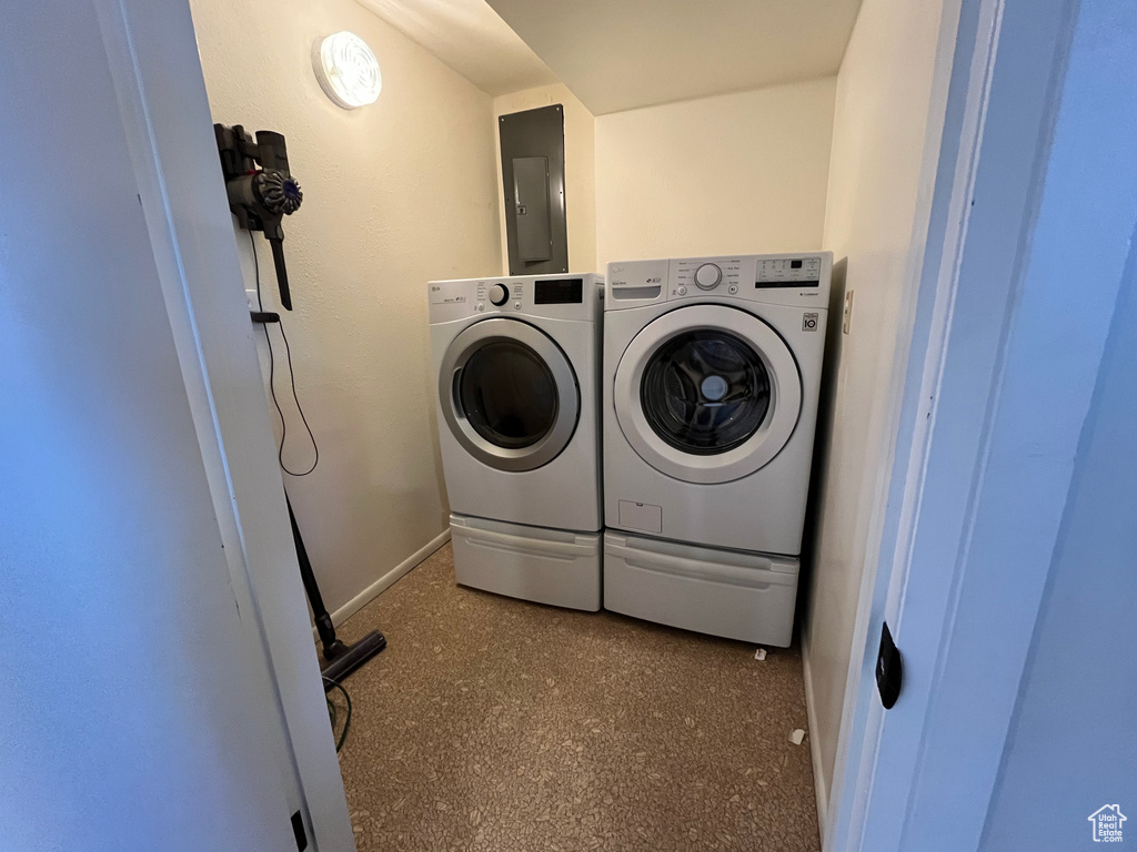 Clothes washing area with electric panel, washer and clothes dryer, and dark colored carpet