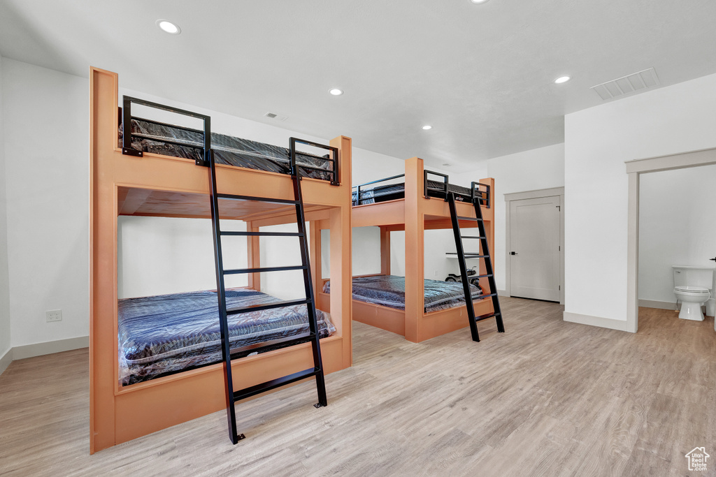 Bedroom with light wood-type flooring and connected bathroom