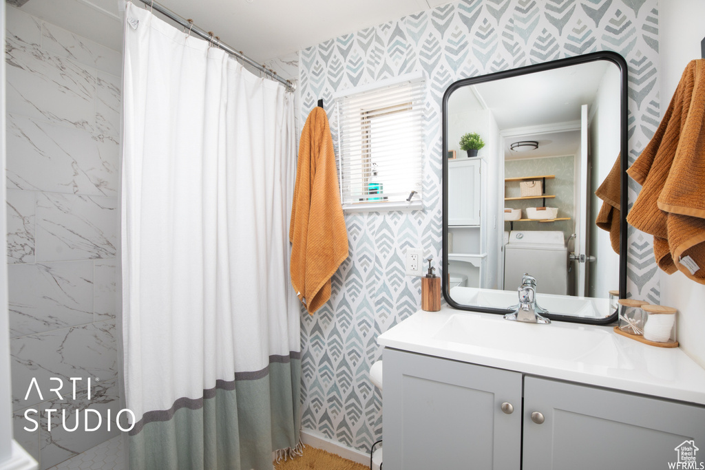 Bathroom featuring vanity, walk in shower, and washer / dryer