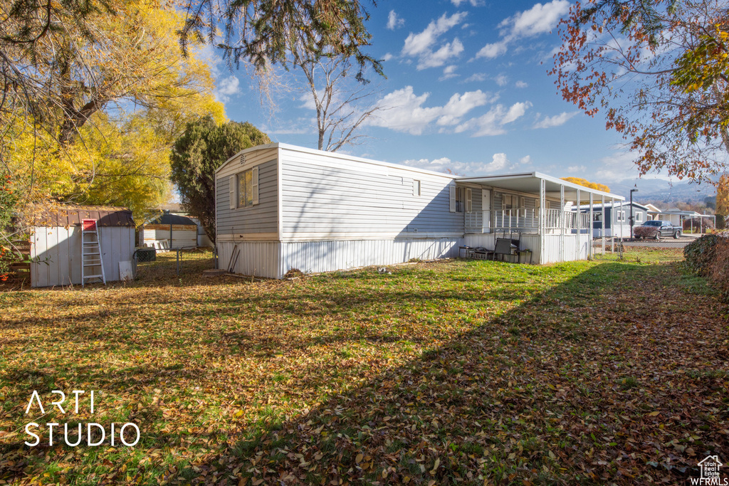 Rear view of property with a storage unit and a lawn