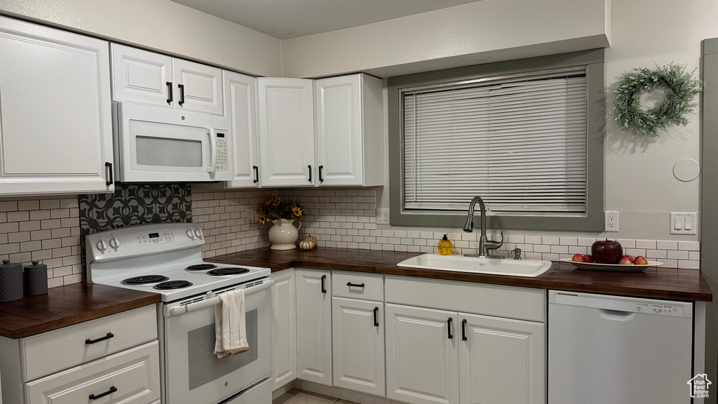 Kitchen featuring decorative backsplash, white cabinetry, wood counters, sink, and white appliances