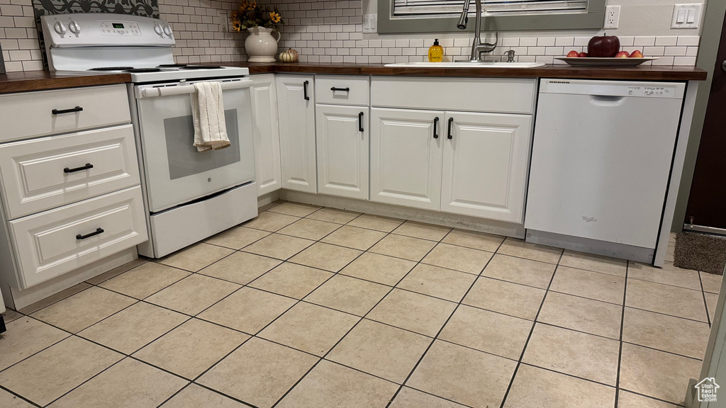 Kitchen featuring white appliances, tasteful backsplash, sink, and white cabinets