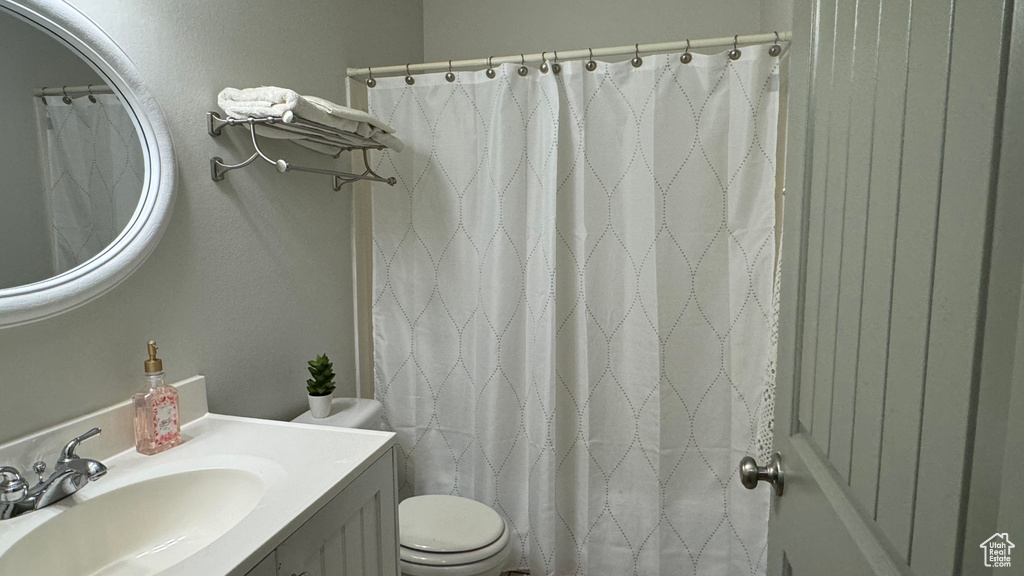 Bathroom with vanity, curtained shower, and toilet