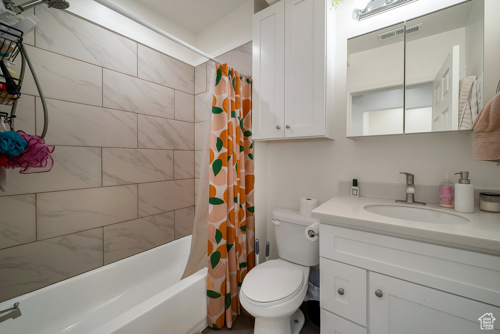 Full bathroom with vanity, shower / bath combo with shower curtain, and toilet