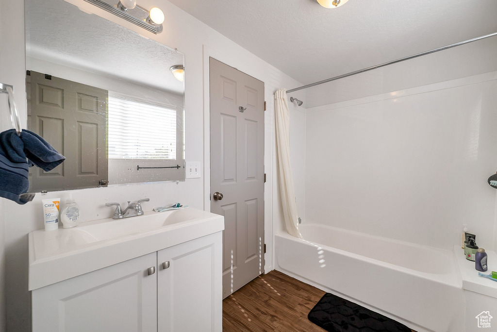 Bathroom featuring shower / bath combo with shower curtain, hardwood / wood-style floors, vanity, and a textured ceiling
