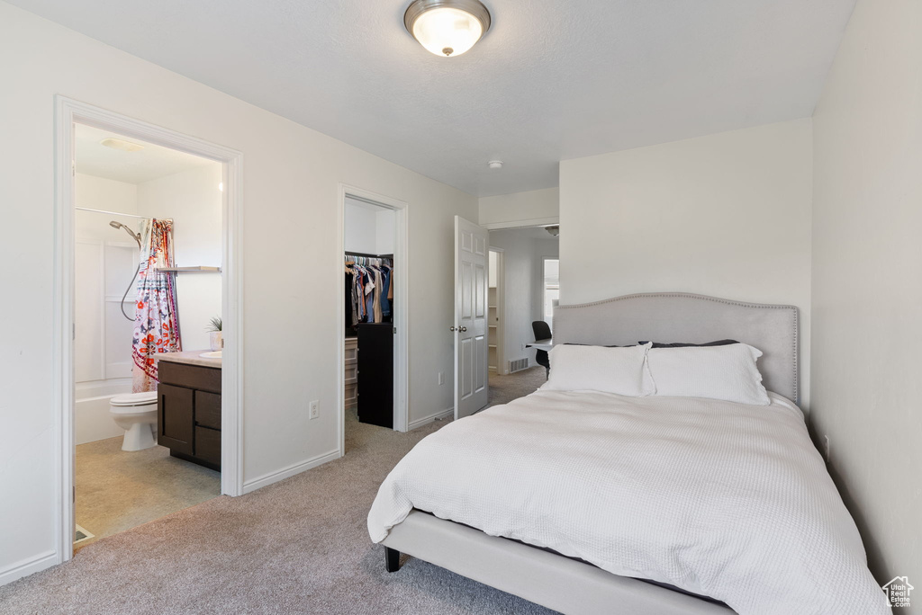 Carpeted bedroom featuring a spacious closet, connected bathroom, and a closet