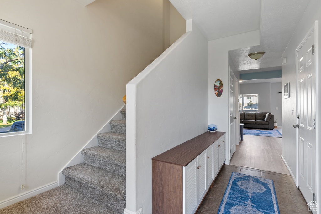 Staircase featuring a wealth of natural light, tile patterned floors, and a textured ceiling