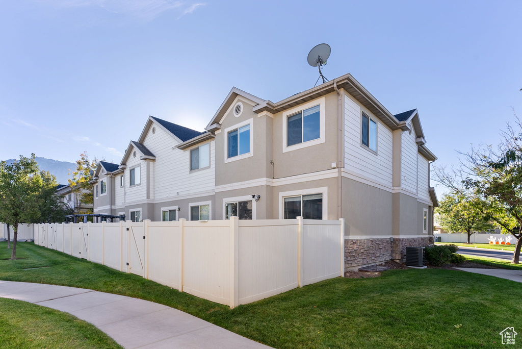 View of side of property featuring a yard and central AC unit