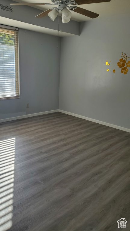 Spare room featuring dark wood-type flooring and ceiling fan