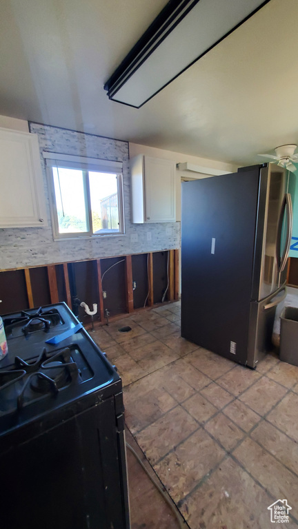 Kitchen featuring tasteful backsplash, electric range, white cabinetry, stainless steel refrigerator, and light tile patterned floors