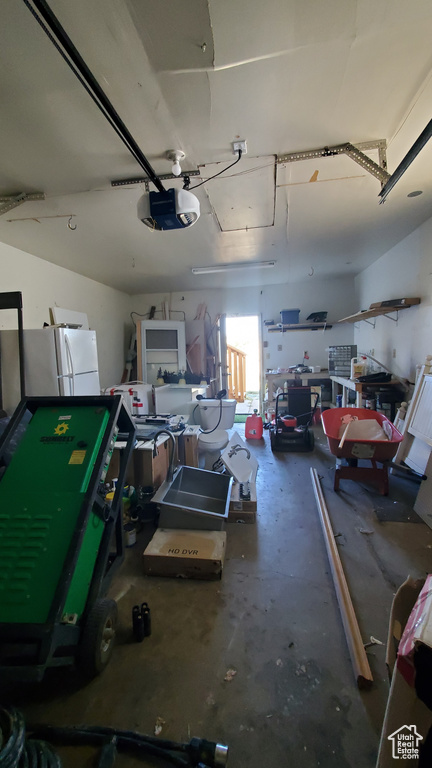 Garage with a garage door opener and white refrigerator