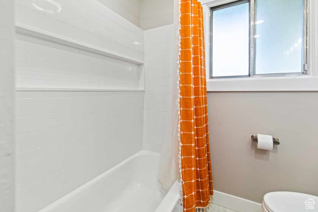 Bathroom with toilet and shower / tub combo with curtain