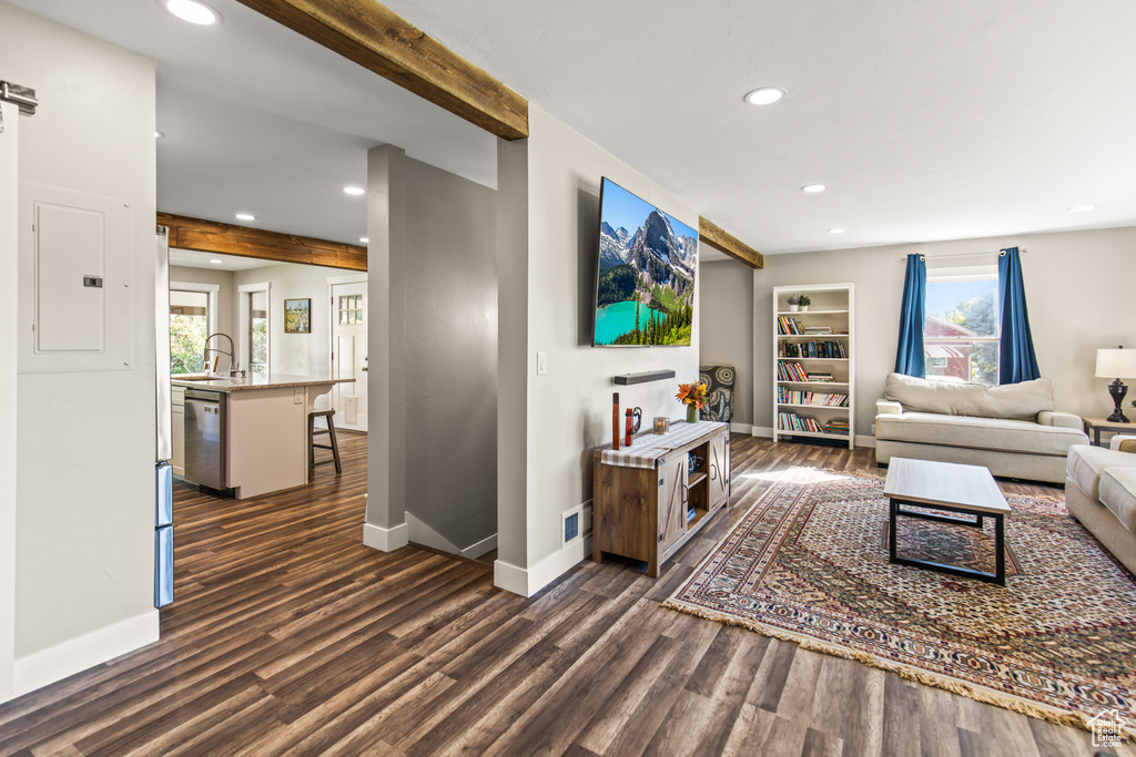 Living room with a healthy amount of sunlight, beamed ceiling, and dark wood-type flooring