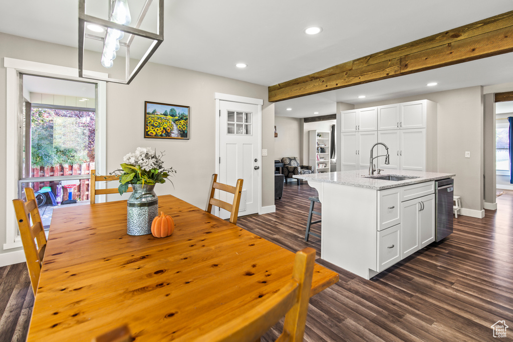 Dining room with dark hardwood / wood-style floors, beam ceiling, and sink