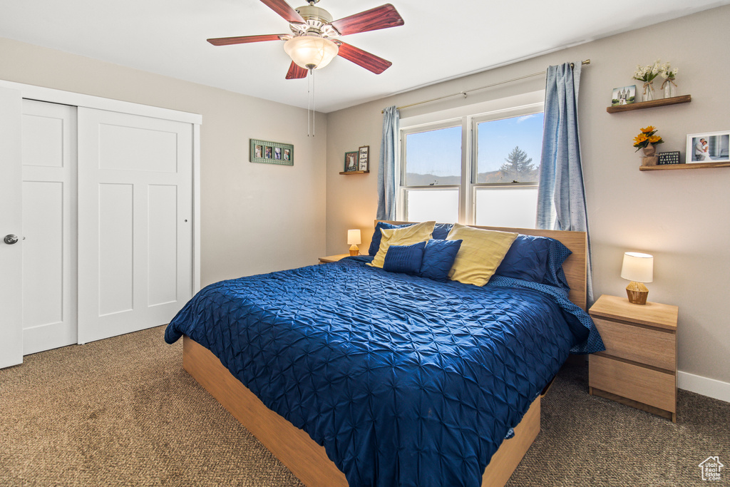 Bedroom with dark colored carpet, a closet, and ceiling fan