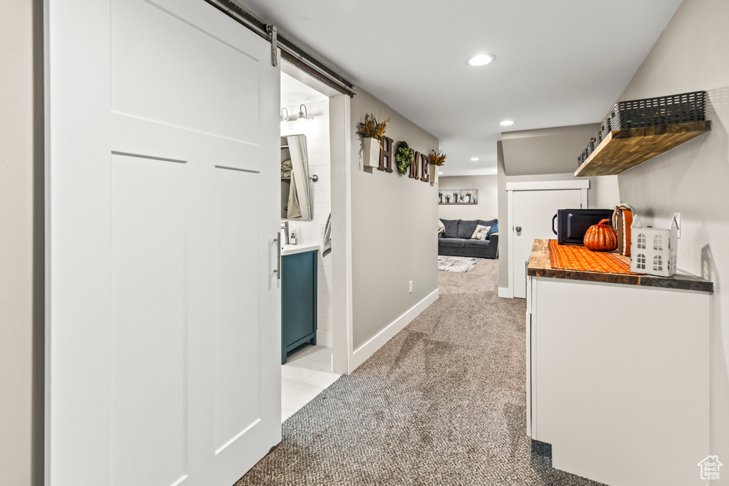 Corridor featuring a barn door and light colored carpet