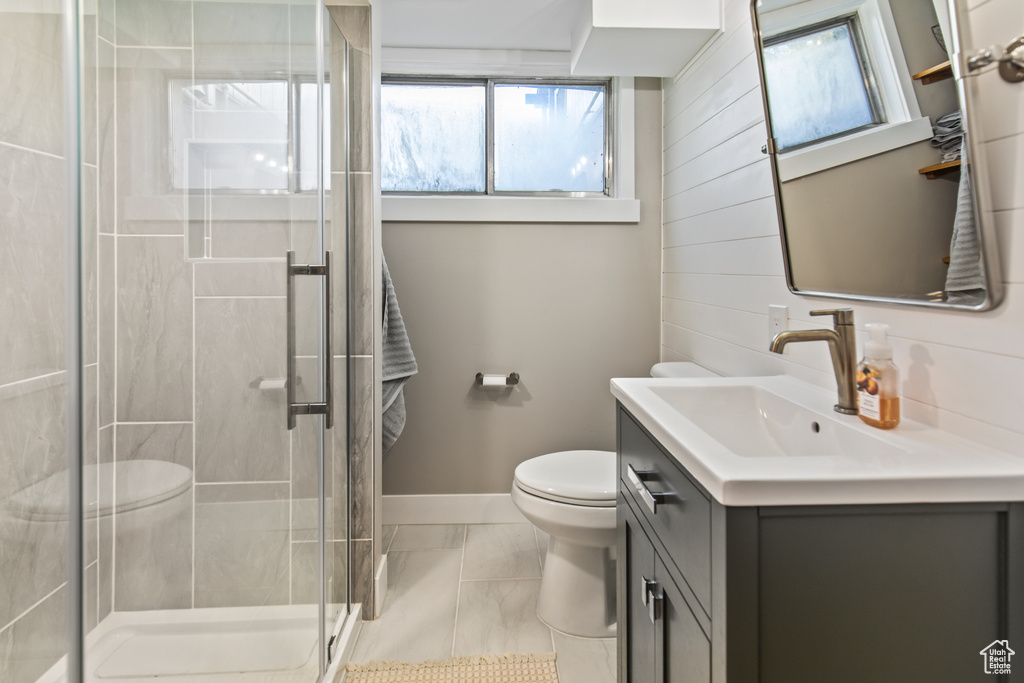 Bathroom with vanity, wooden walls, a shower with shower door, and toilet