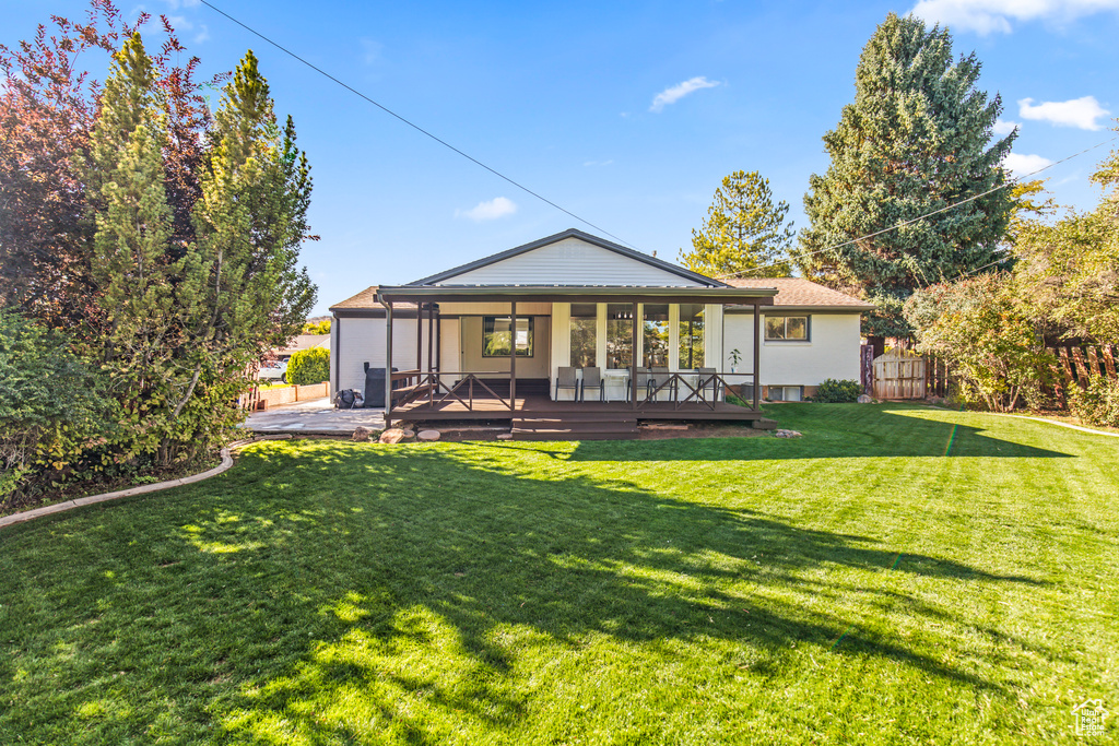 Rear view of property with a wooden deck and a yard