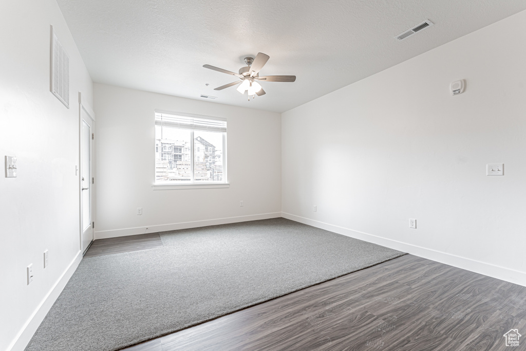 Spare room with dark wood finished floors, baseboards, visible vents, and ceiling fan