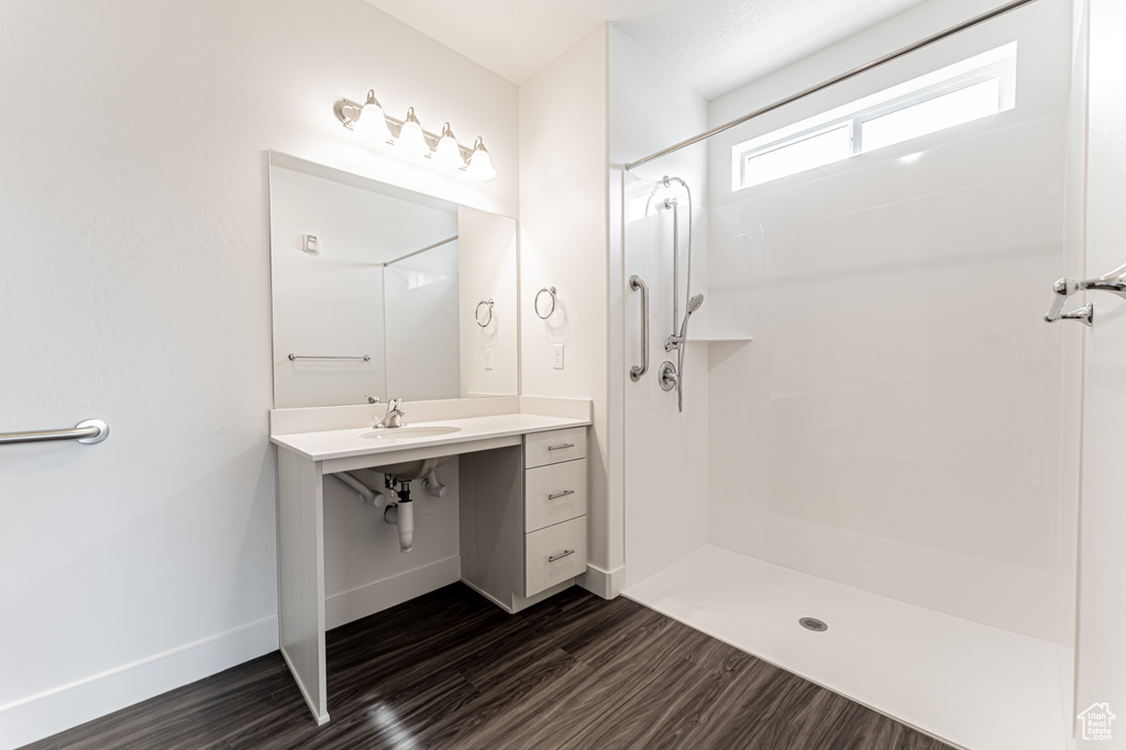 Full bath featuring a sink, baseboards, walk in shower, and wood finished floors