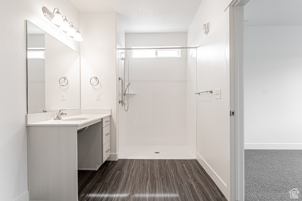 Bathroom with vanity, wood finished floors, a walk in shower, and baseboards