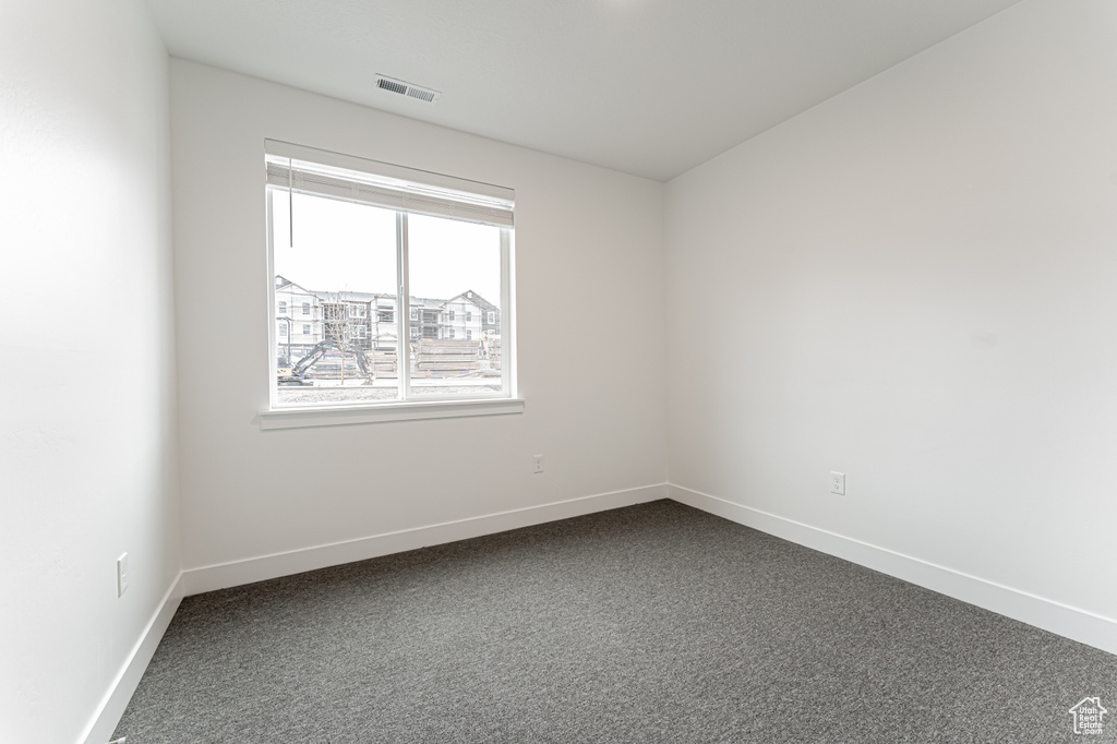 Unfurnished room with visible vents, baseboards, and dark colored carpet