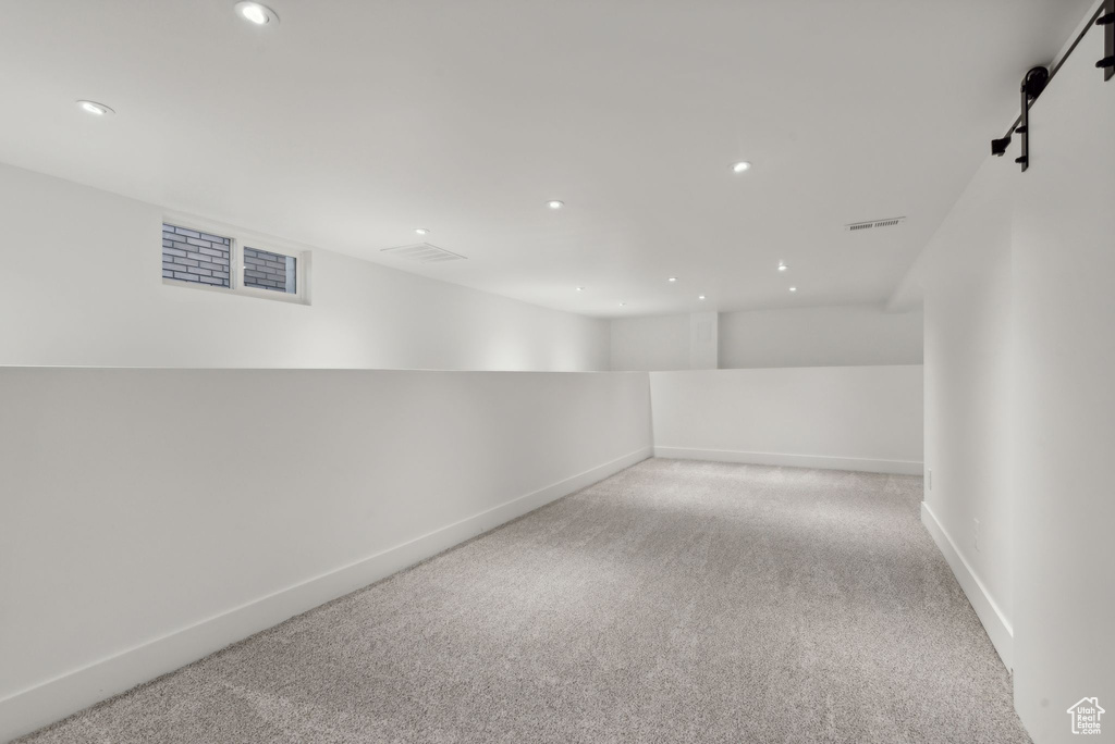 Spare room featuring a barn door and light colored carpet