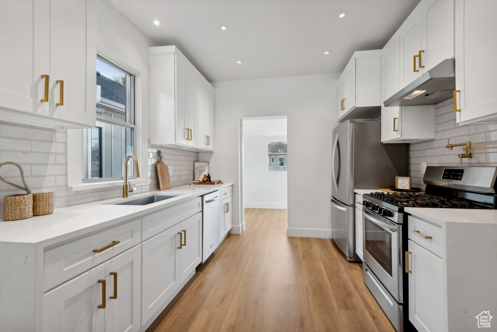 Kitchen featuring white cabinetry, stainless steel appliances, decorative backsplash, and sink