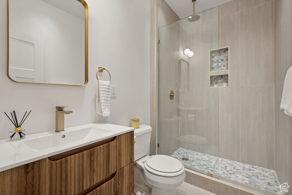 Bathroom with a shower with door, vanity, and toilet