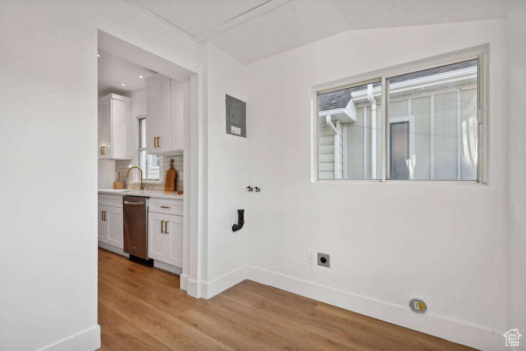 Washroom with hookup for an electric dryer, sink, and light wood-type flooring