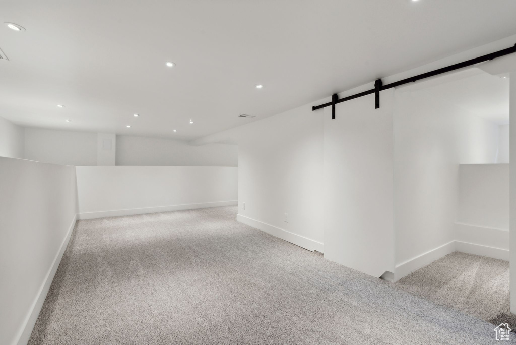 Unfurnished room with a barn door and light colored carpet