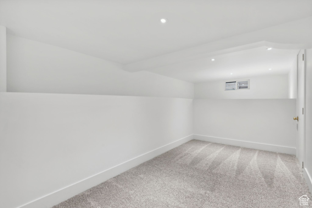 Carpeted spare room with vaulted ceiling with beams