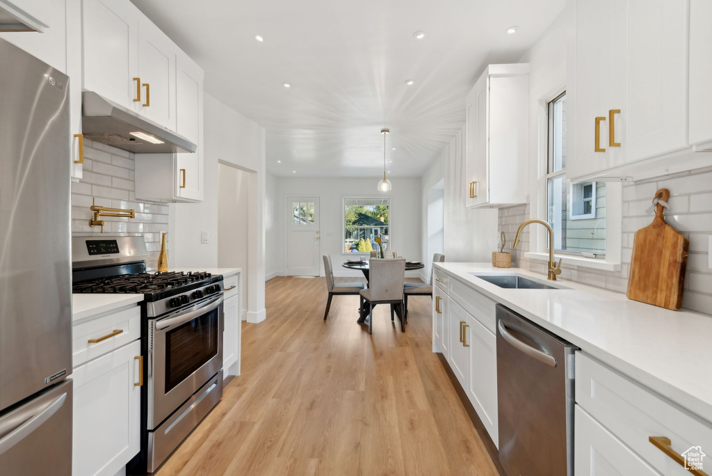 Kitchen with sink, white cabinetry, stainless steel appliances, and tasteful backsplash