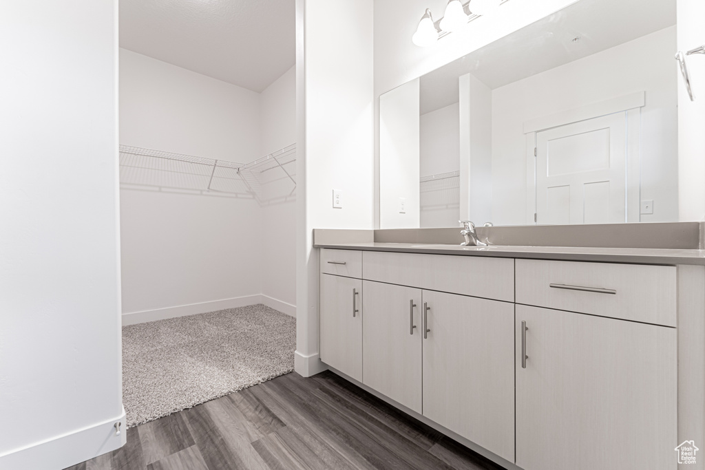 Bathroom featuring vanity, wood finished floors, a spacious closet, and baseboards
