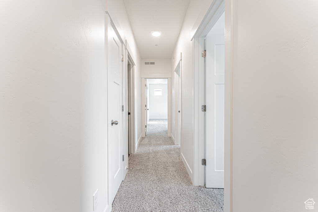 Hall featuring light carpet and baseboards