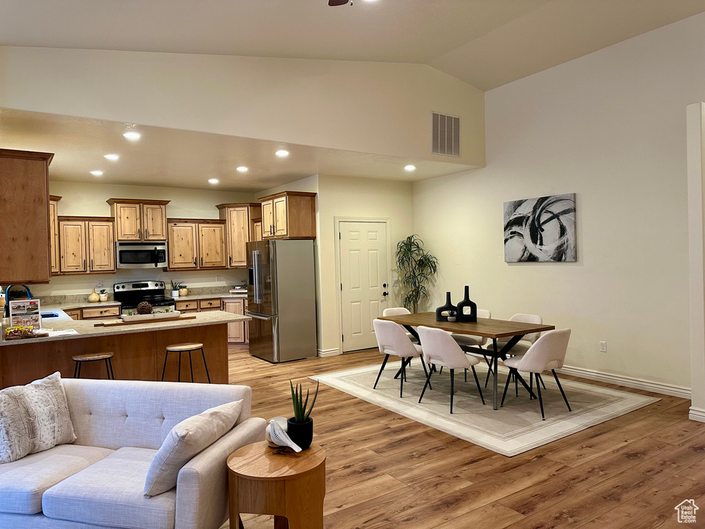 Kitchen featuring lofted ceiling, sink, appliances with stainless steel finishes, light hardwood / wood-style floors, and kitchen peninsula