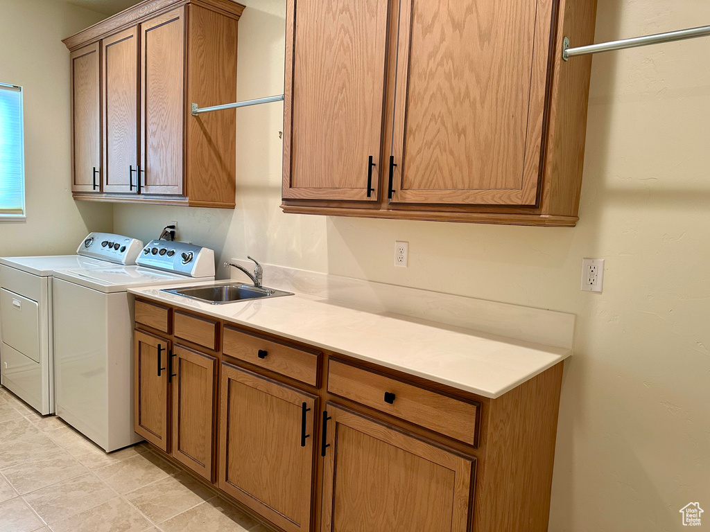 Clothes washing area featuring cabinets, independent washer and dryer, sink, and light tile patterned floors