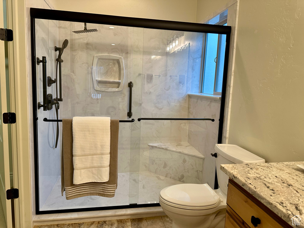 Bathroom featuring vanity, toilet, and a shower with shower door