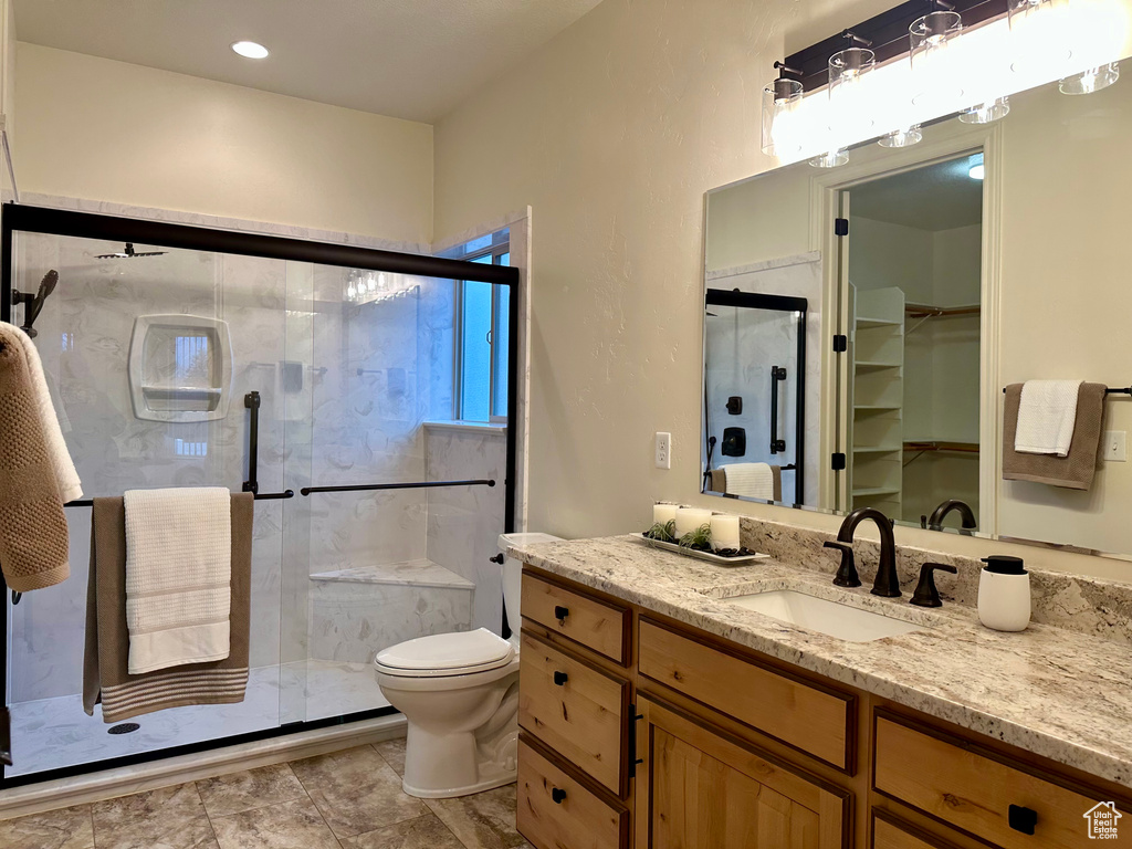 Bathroom featuring vanity, toilet, and a shower with shower door