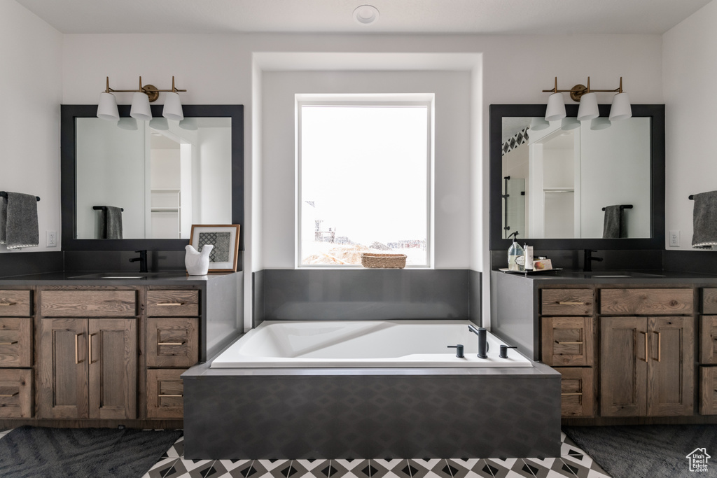 Bathroom featuring tiled tub and vanity