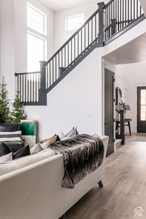 Living room with a towering ceiling and light hardwood / wood-style flooring