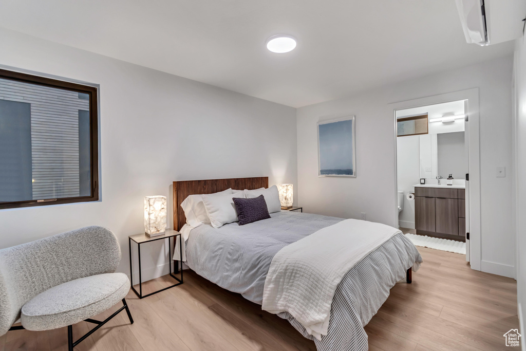 Bedroom with light hardwood / wood-style flooring, ensuite bathroom, and sink