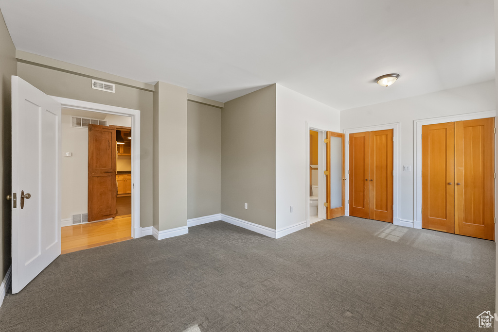 Unfurnished bedroom with ensuite bathroom and carpet