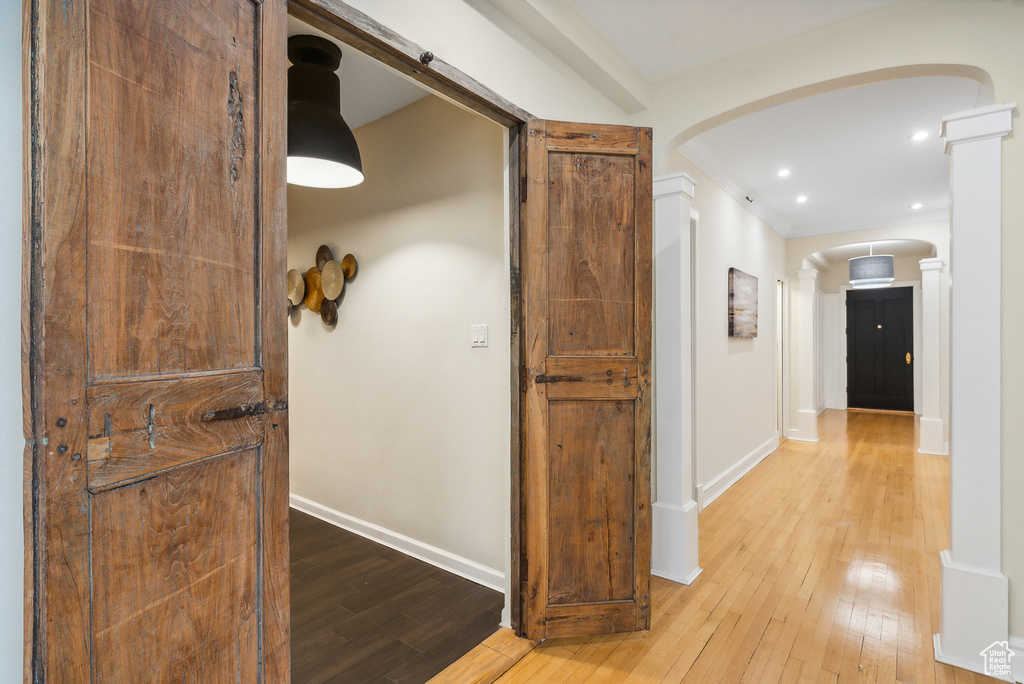 Hall with ornate columns and light hardwood / wood-style floors