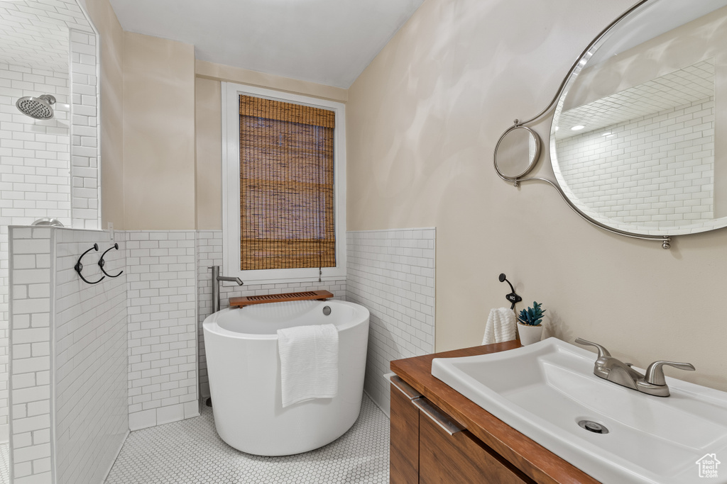 Bathroom with tile walls, vanity, tile patterned floors, and a tub
