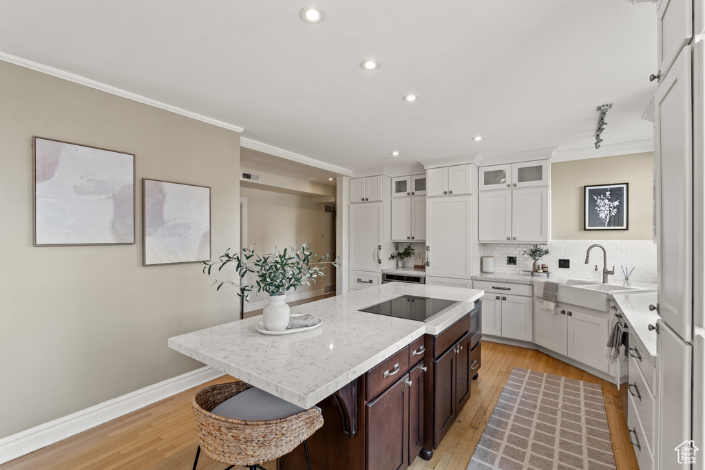 Kitchen featuring dark brown cabinetry, white cabinetry, crown molding, and a kitchen island