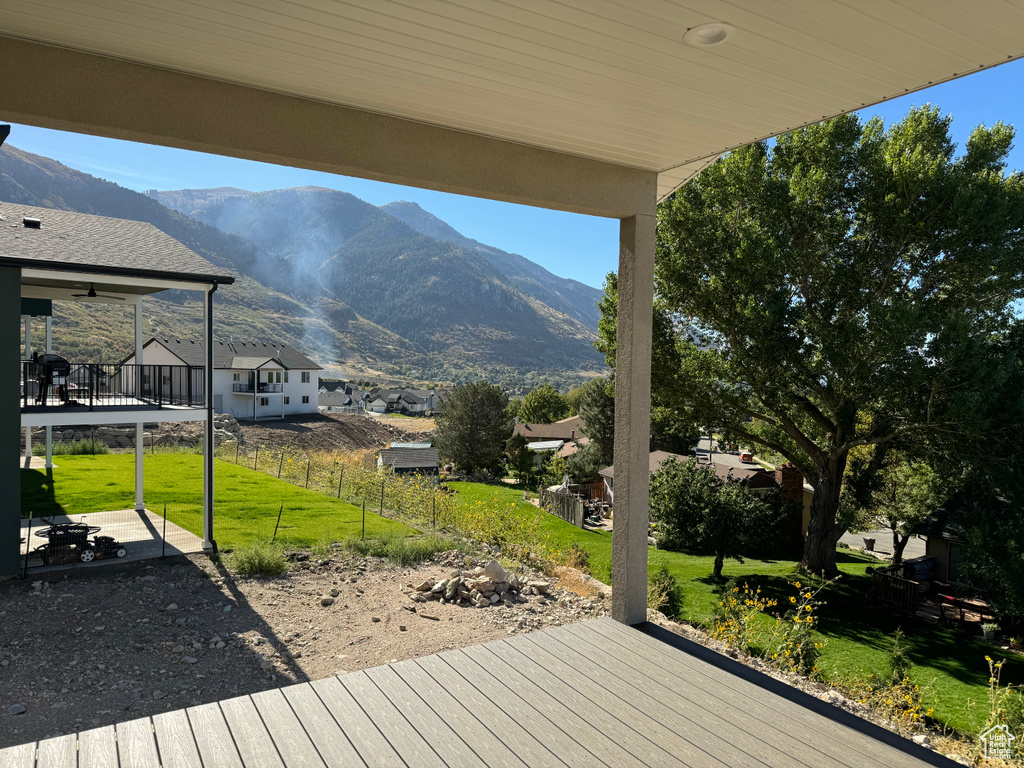 Wooden terrace featuring a mountain view and a lawn