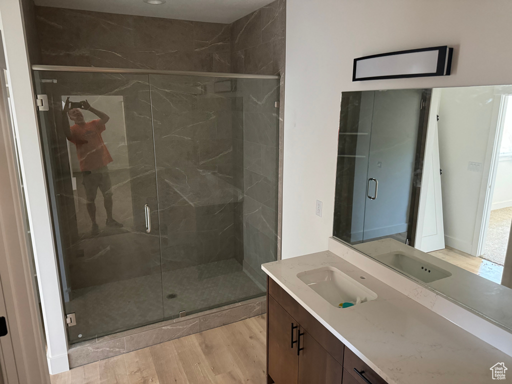 Bathroom with vanity, hardwood / wood-style floors, and a shower with door